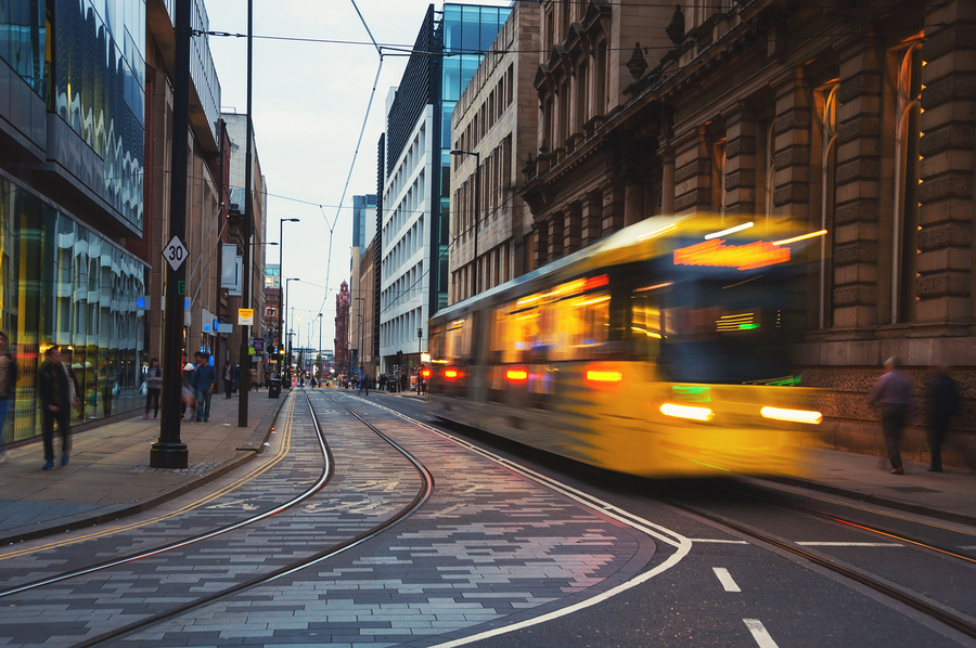 Offices in Manchester, England with Yellow tram passing through the street.