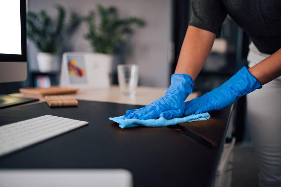 Spotless cleaning operative wiping up spillage on office desk.